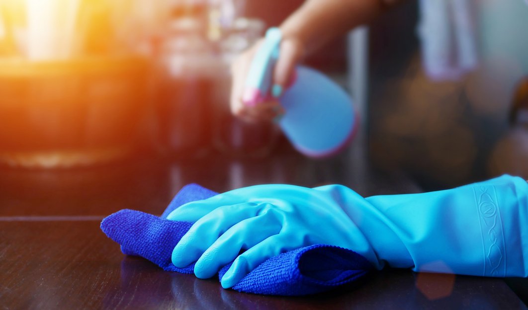 Person mit blauem Handschuh desinfiziert eine Oberfläche