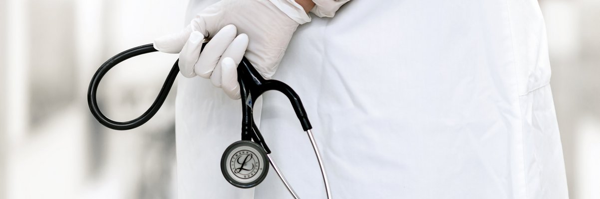 Mediziner hält ein Stetoskop mit verschränkten Armen auf dem Rücken