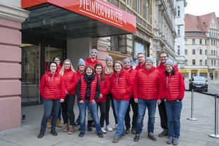 Gruppenfoto vor dem Eingang des Steintor-Varieté. Alle tragen rote Pullover und Westen. 