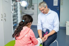 Prof. Dr. Martin Kaiser untersucht das Bein eines Mädchens in einem Untersuchungsraum des Universitätsklinikums Halle (Saale).