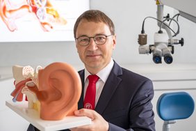 Prof. Dr. Stefan Plontke präsentiert ein anatomisches Modell eines Ohres.