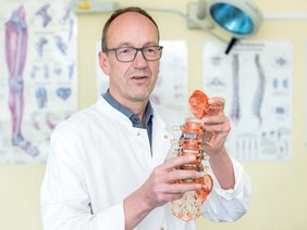 Prof. Dr. Karl-Stefan Delank hält ein Wirbelsäulen-Modell in den Händen.